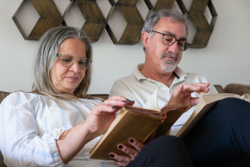 old lady and man wearing readers while reading their books