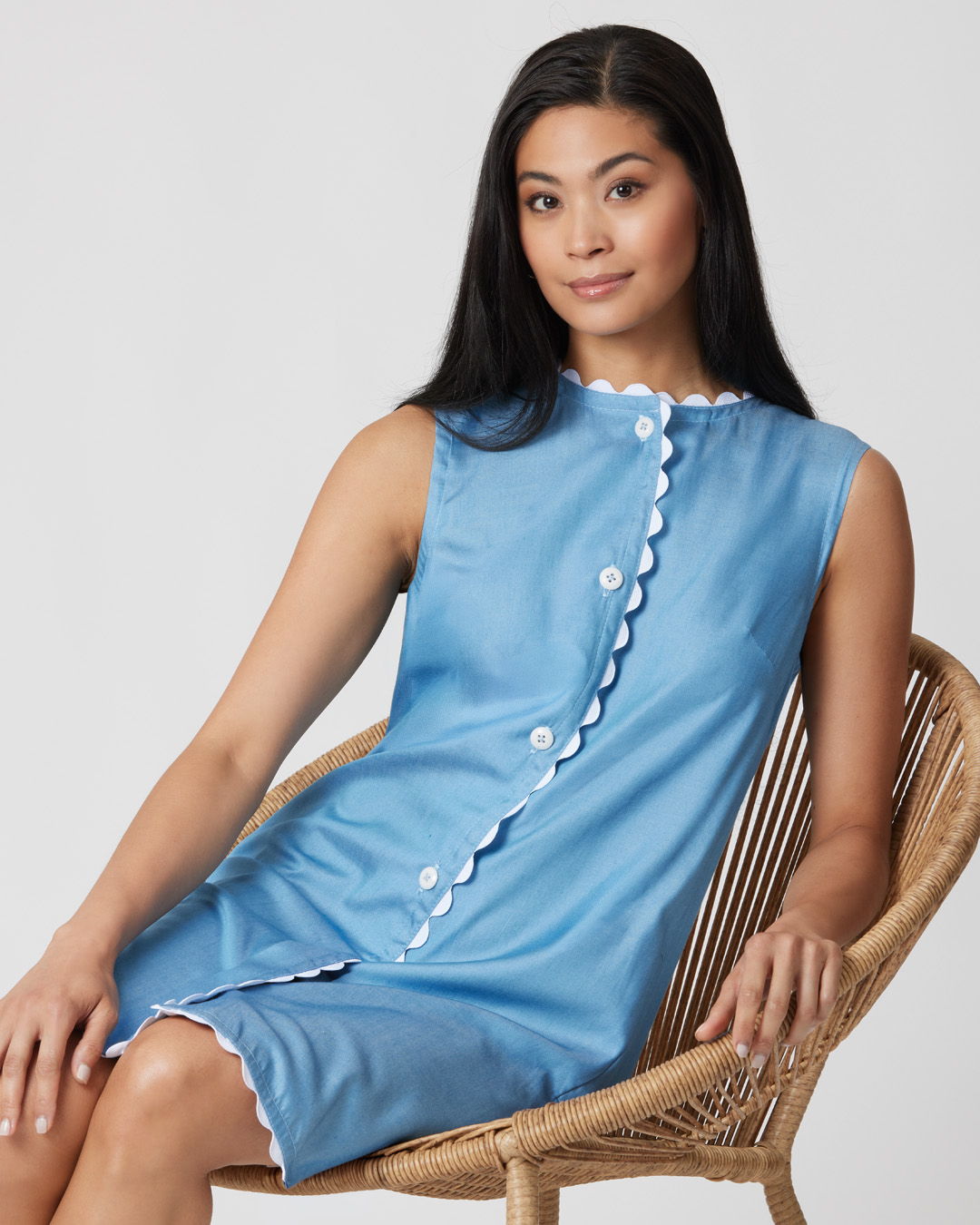 Woman in a blue dress sitting on a rattan chair.