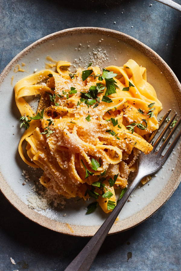Pappardelle pasta in a creamy butternut squash sauce topped with grated cheese and served on a plate