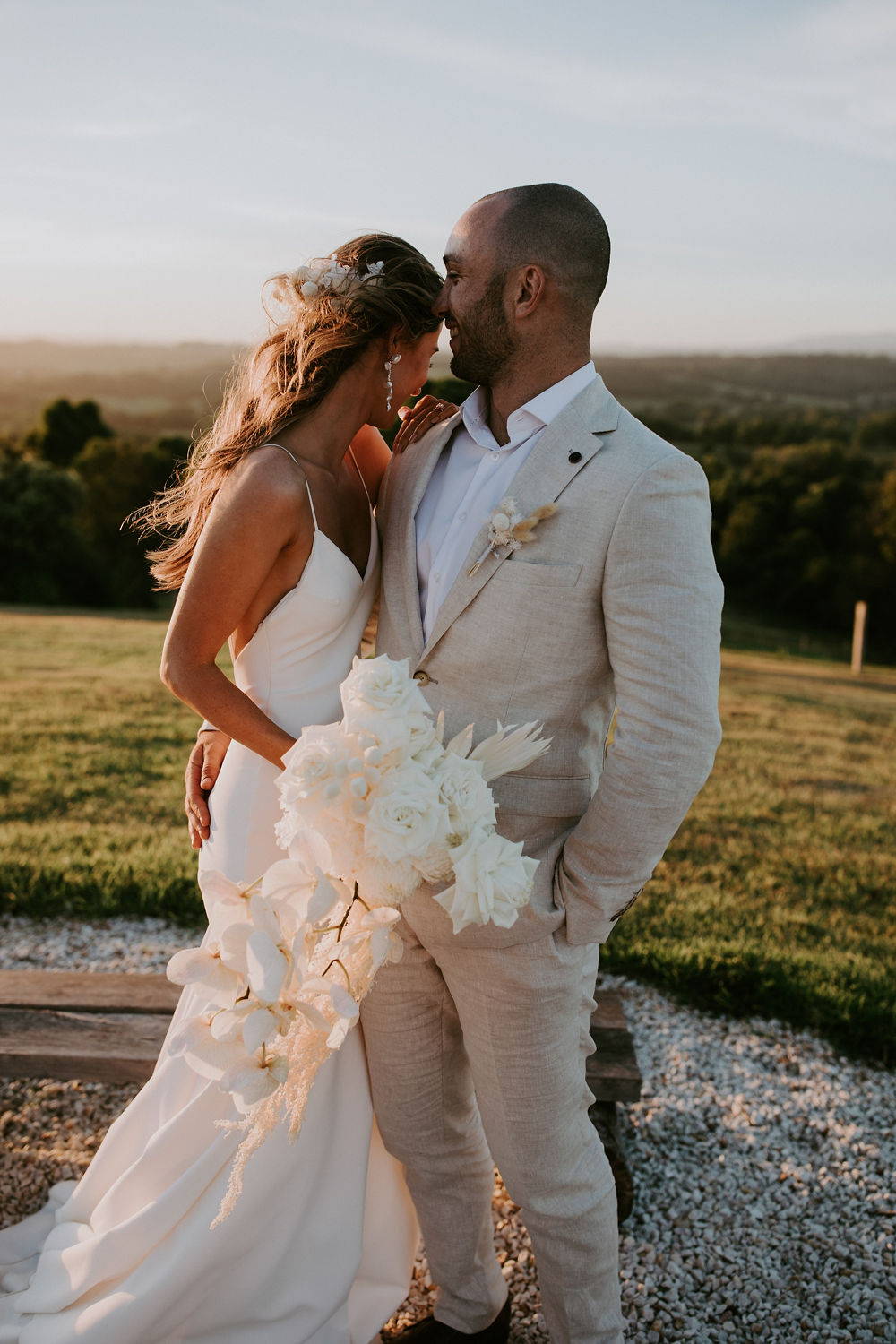 groom wearing a beige suit hugging his new wife in the Byron Hinterland