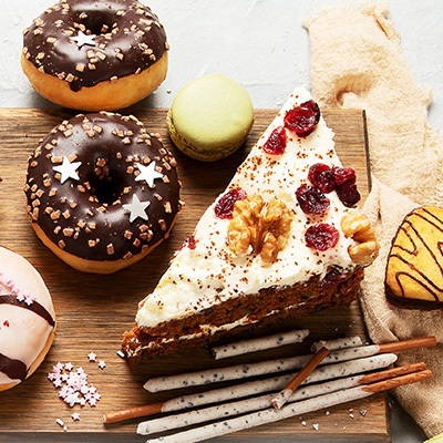 A photo showing a slice of carrot cake and two chocolate doughnuts.