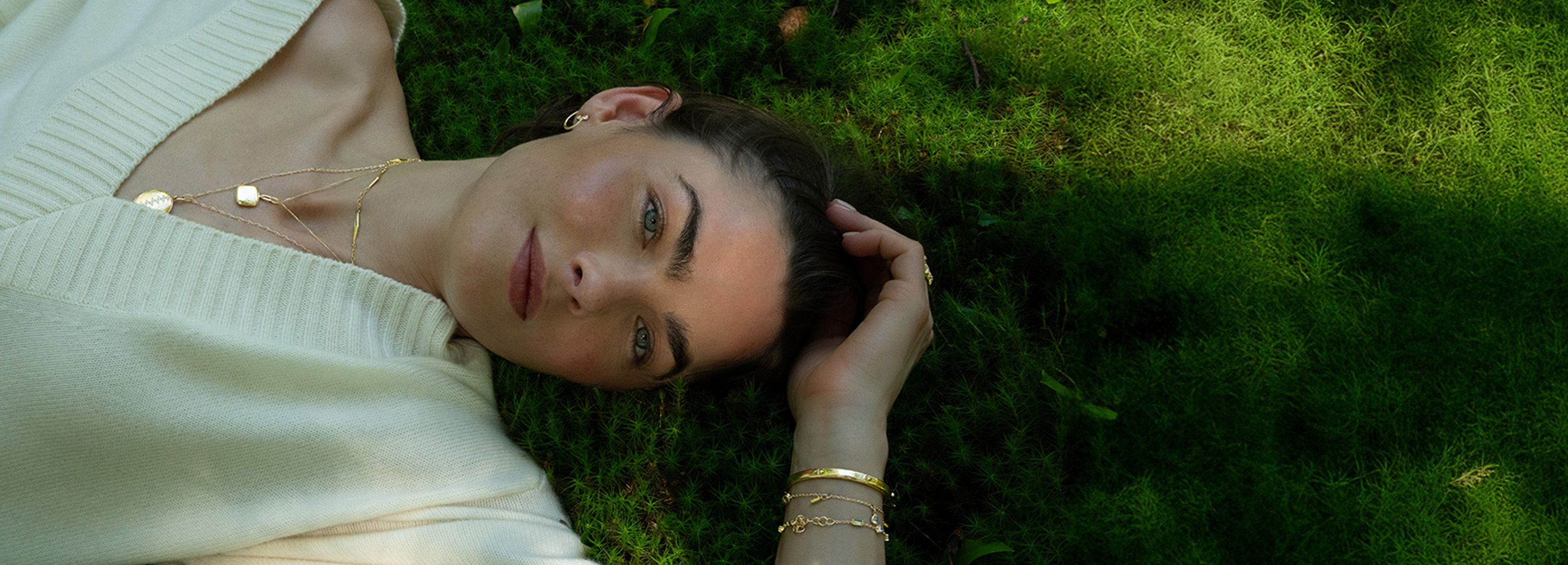 Person lying on grass, resting with hand on head, serene expression.