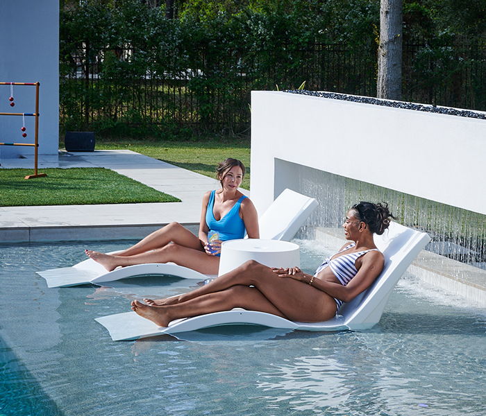 Two women relaxing on loungers in a pool area.