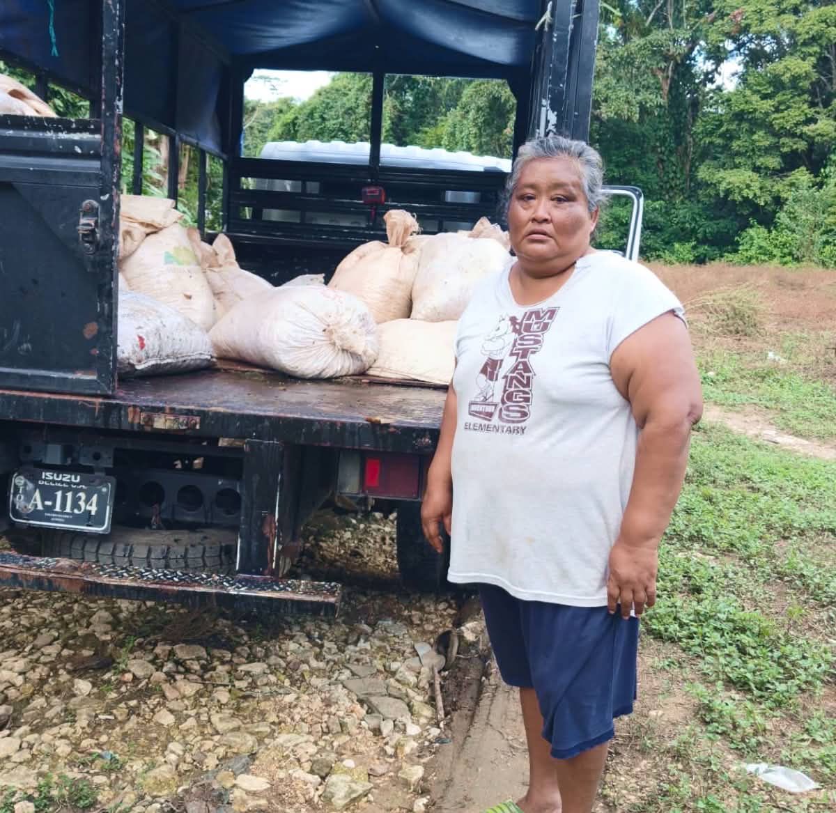 A woman stands next to a truck loaded with bags.
