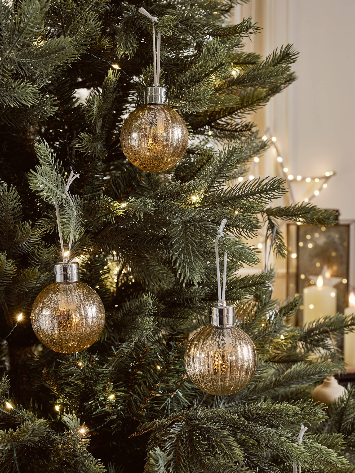 3 gold LED baubles on a Christmas tree.