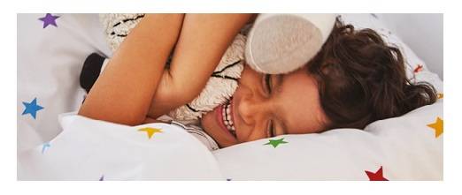 Young boy playing on top of rainbow stardust bedding