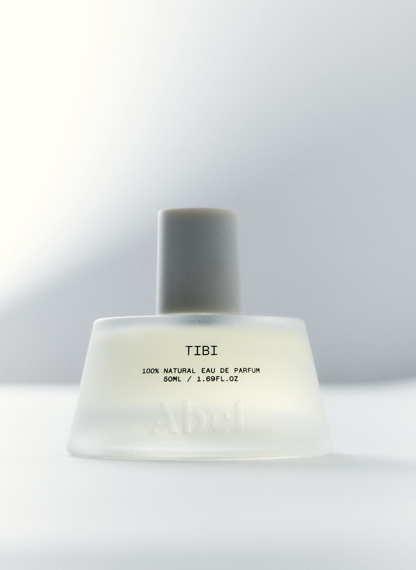 A clear perfume bottle with a gray cap and labeled