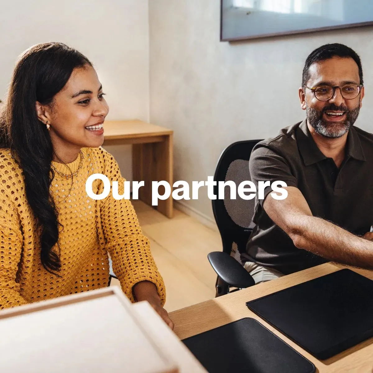 Two people smiling at a desk with 