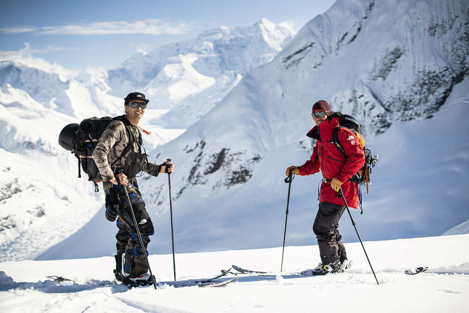 Two climbers in winter gear on a snowy mountain landscape.