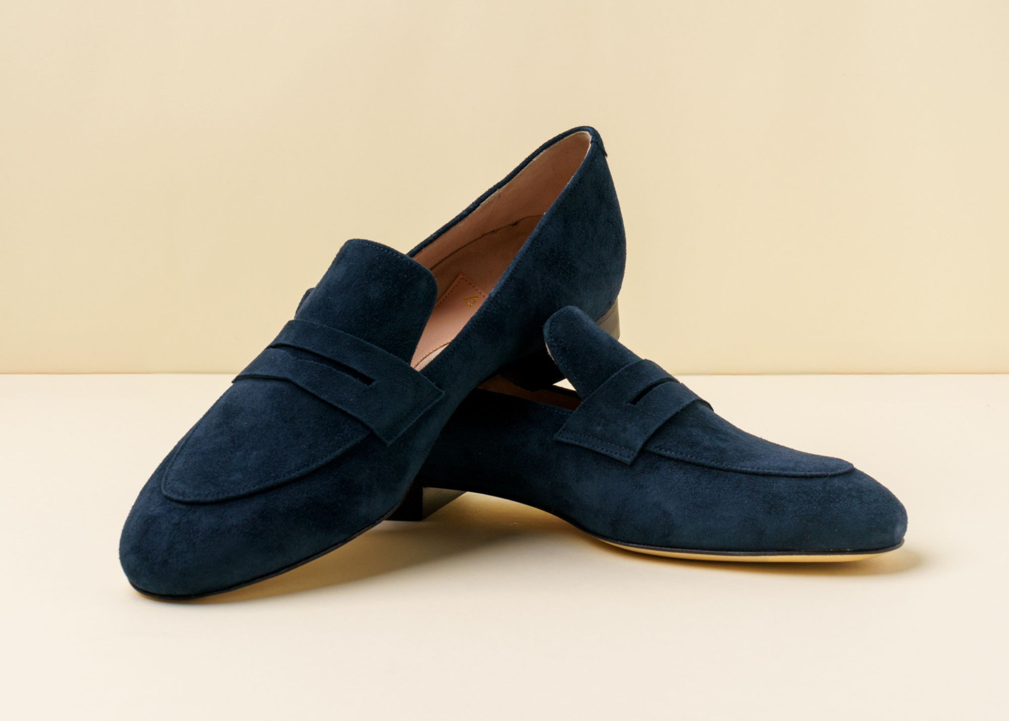 Navy suede loafers on a neutral background.