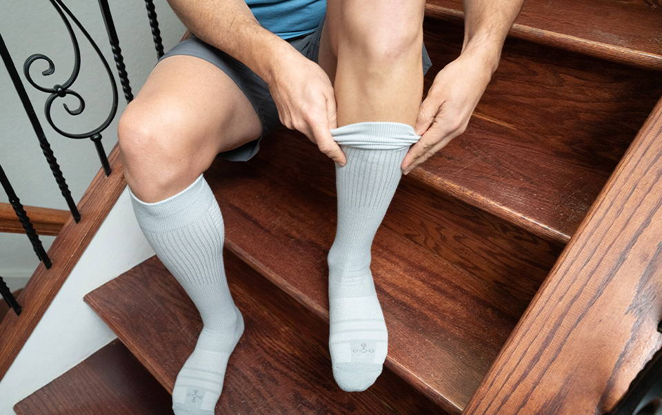 A man putting on Tommie Copper compression socks
