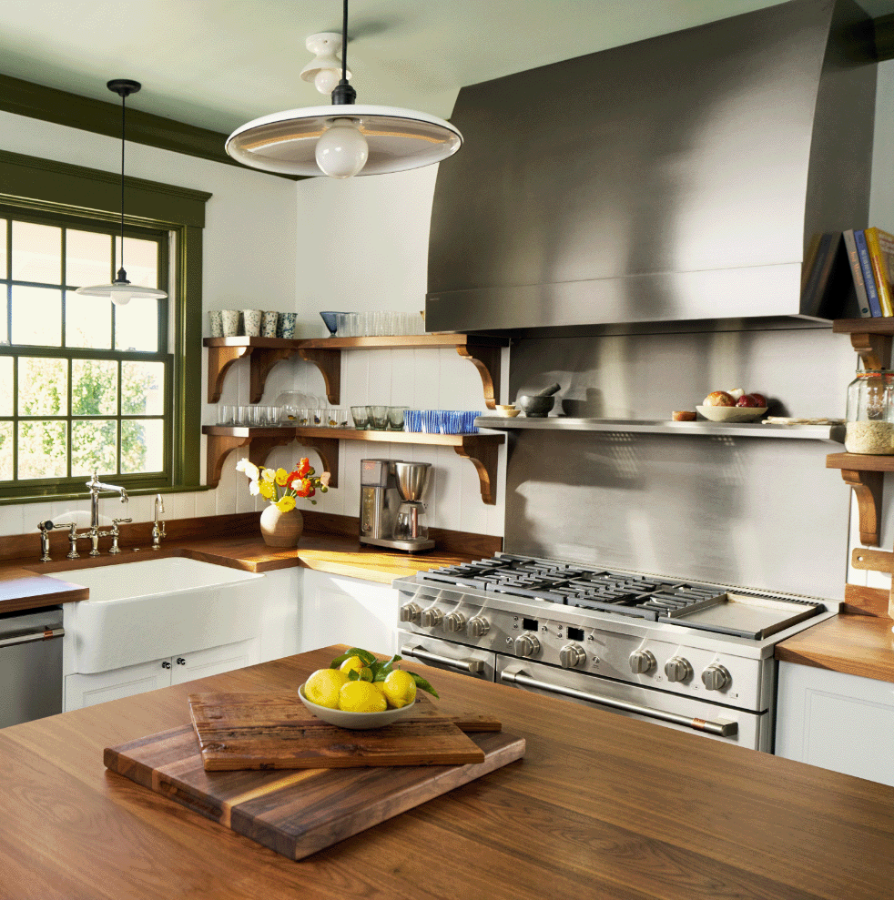 Modern kitchen with wooden shelves, stainless steel appliances, and a fruit bowl.