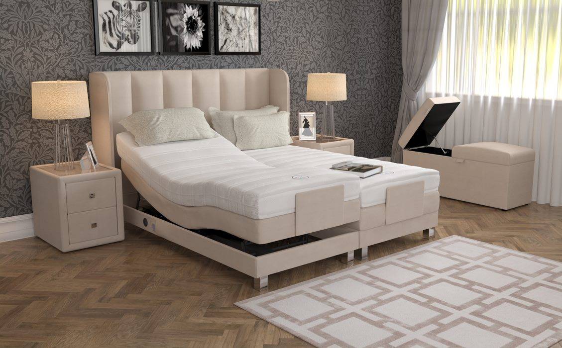 A clean, neutral toned bedroom with an adjustable bed in centre. OIne side of bed has the head adjusted upwards slightly.