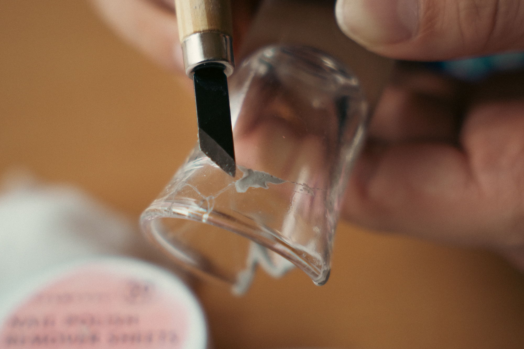 A person using a tool to craft a clear plastic object.