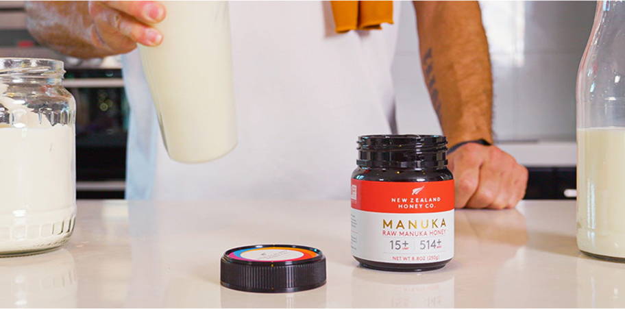 A person pouring milk next to a jar and container on a countertop.