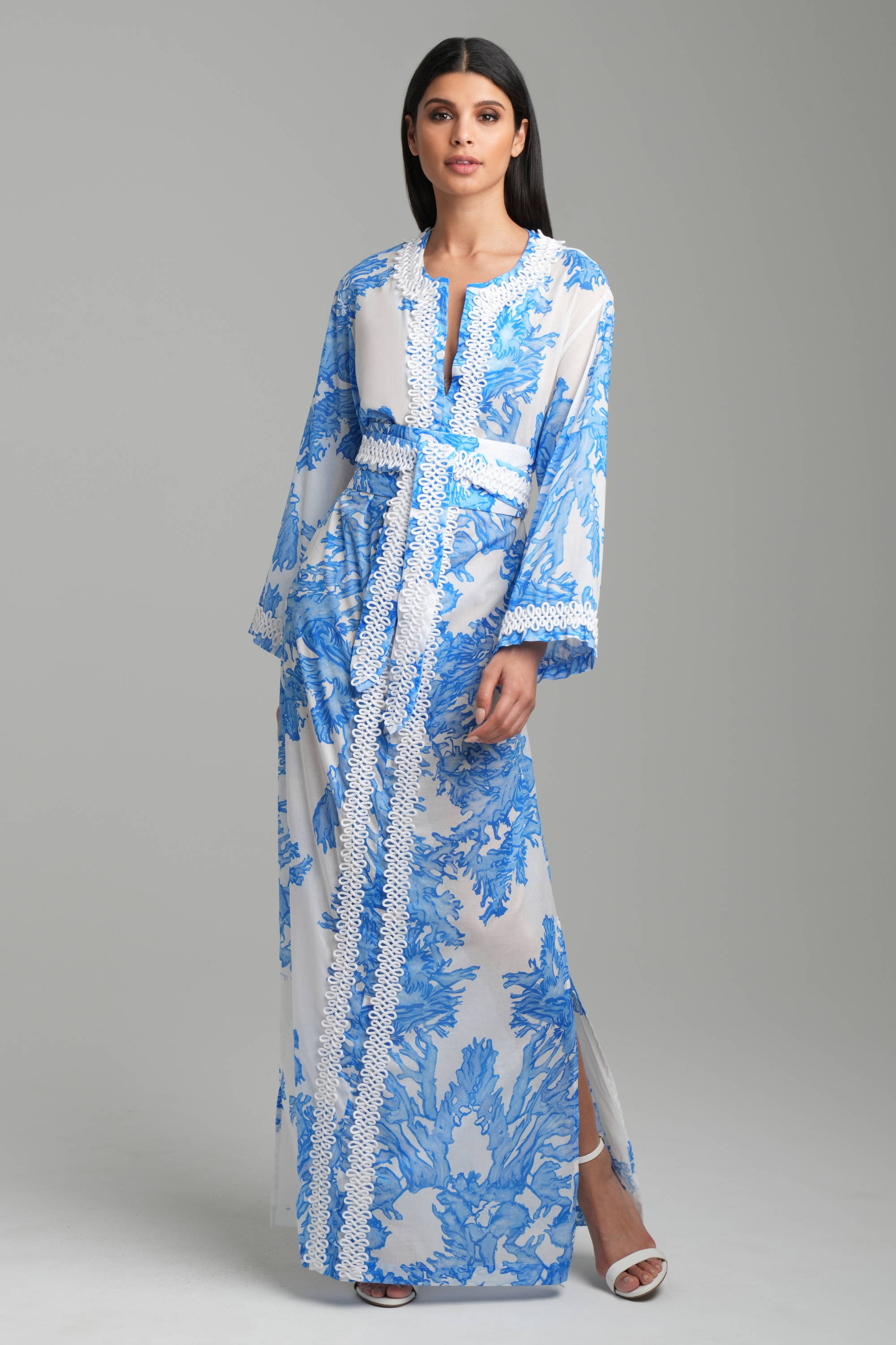 Woman wearing blue coral printed kaftan with white trim and matching belt by Ala von Auersperg