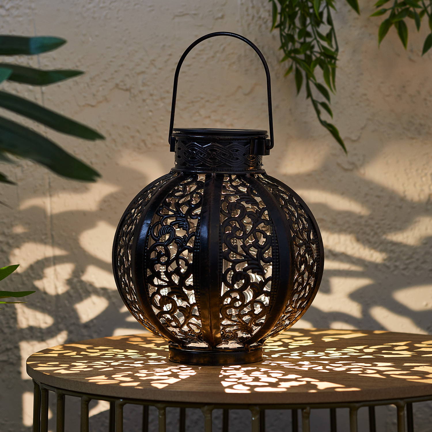 Casablanca lantern sat on table and illuminated with patterned glow 