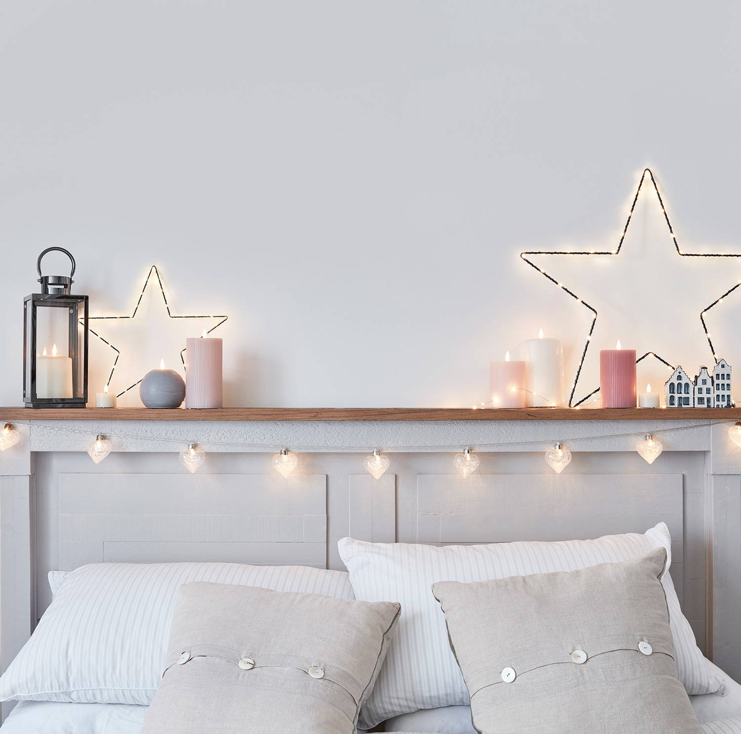 A bright bedroom setting with fairy lights, LED candles and star lights.