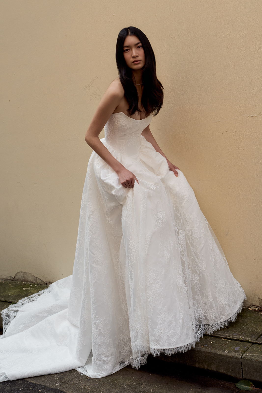 Model wearing a strapless white wedding dress against a plain background.