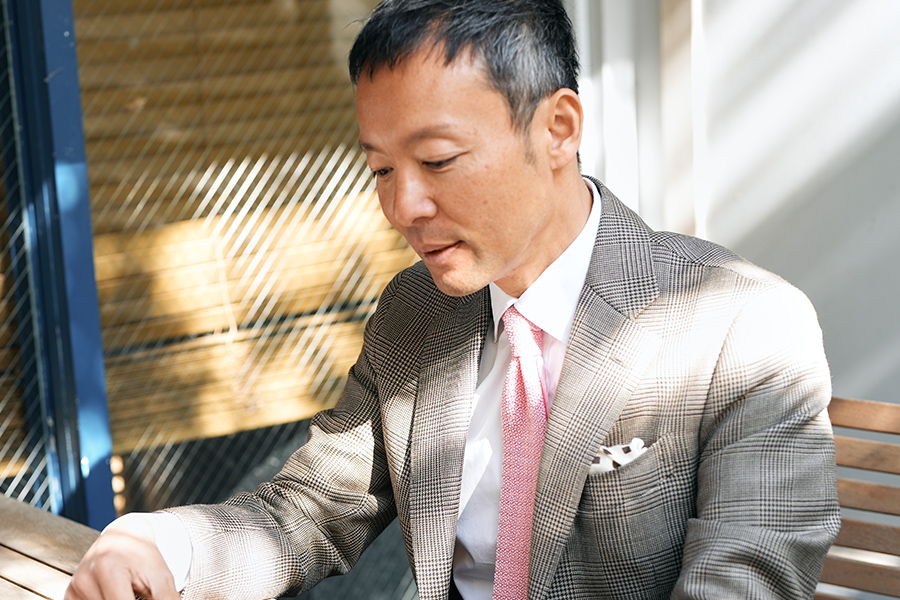 A man in a suit and pink tie sitting at a table.