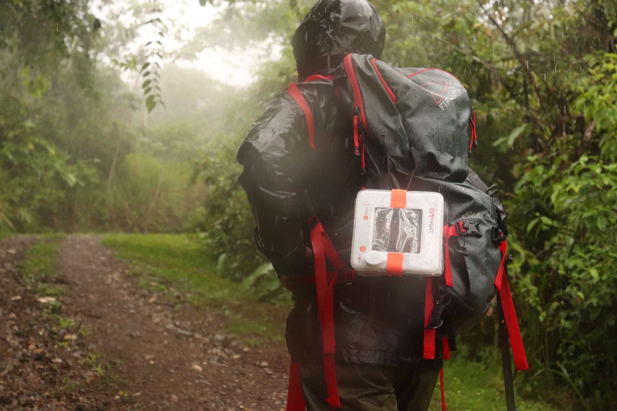 Man backpacking in rain with light on backpack.