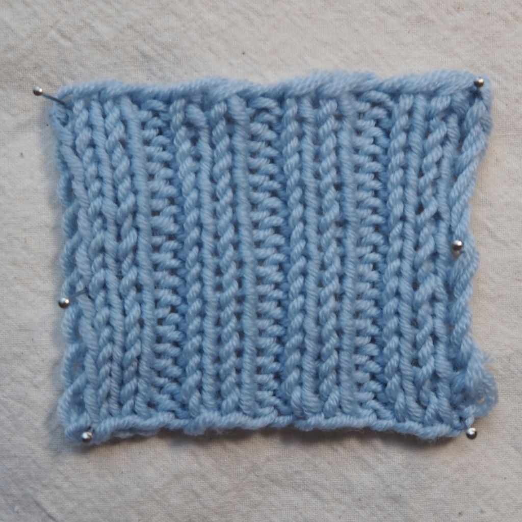 Maschenprobe einer 2x2-Rippe aus einem hellblauem Garn.