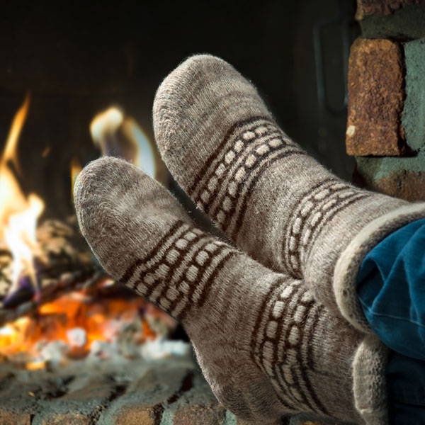 person's feet with warm cozy socks on in front of fireplace