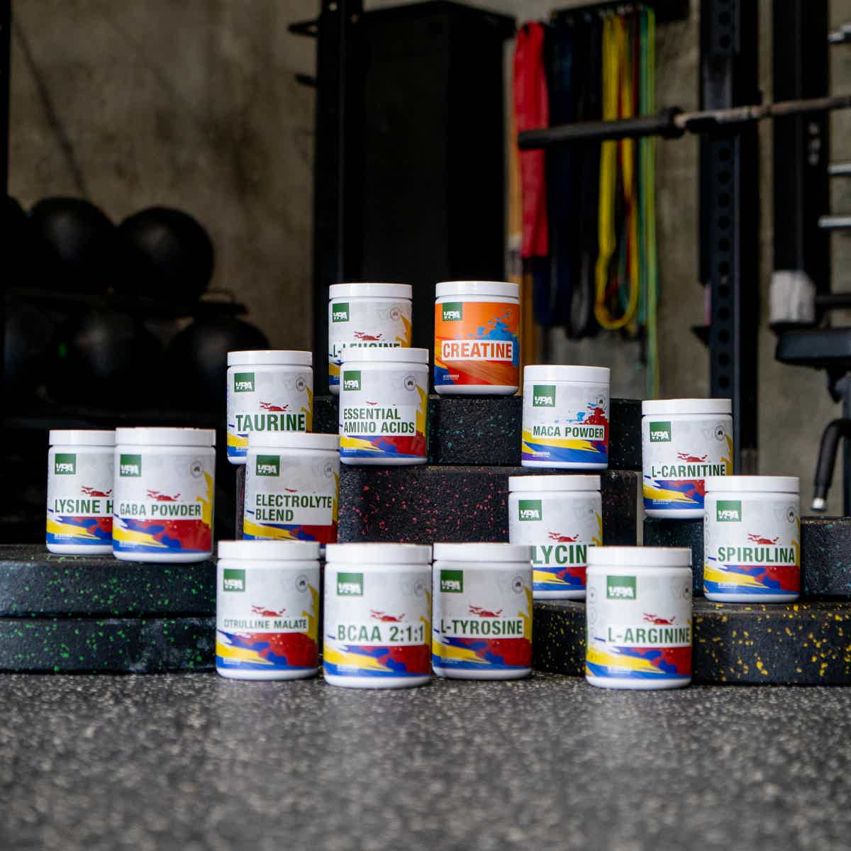 Assorted supplement containers arranged on gym equipment background.
