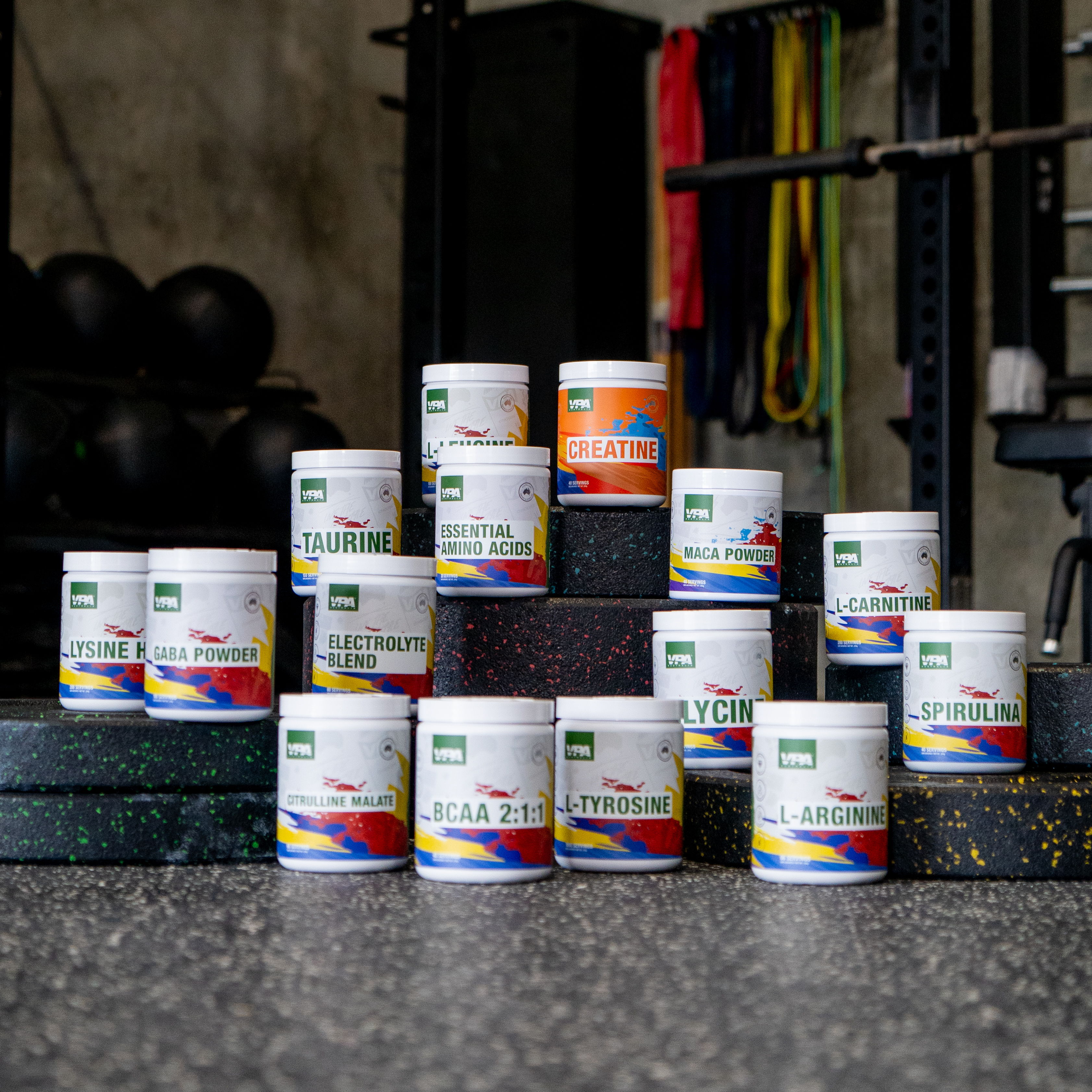 Assorted supplement containers arranged on gym equipment background.