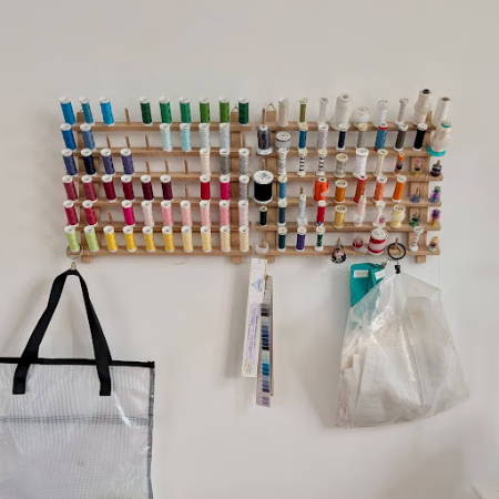 thread rack on the wall with colorful bobbins
