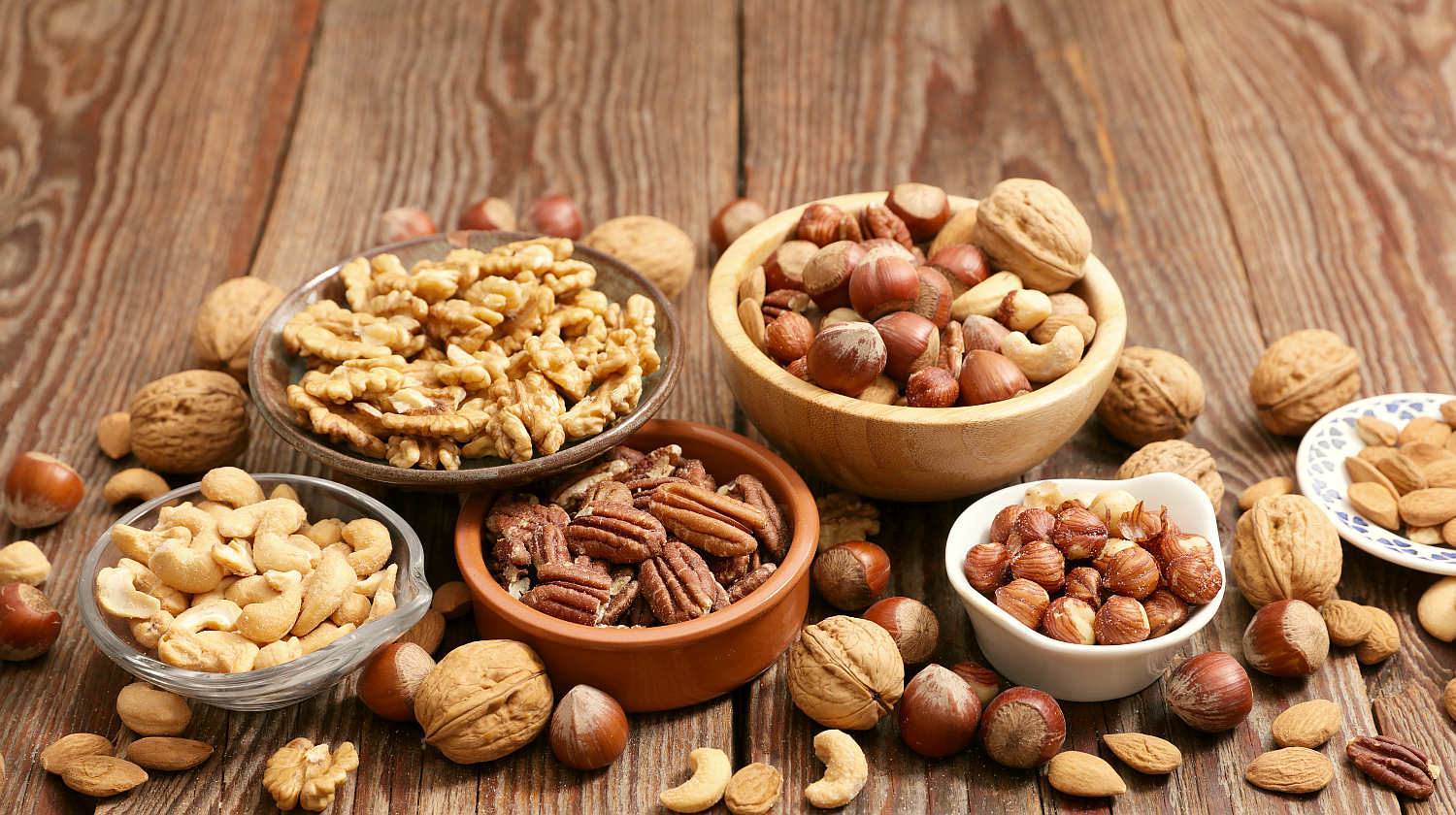 Assorted nut on wooden background | What’s The Difference Between Various Nuts and Seeds? | types of nuts | Featured