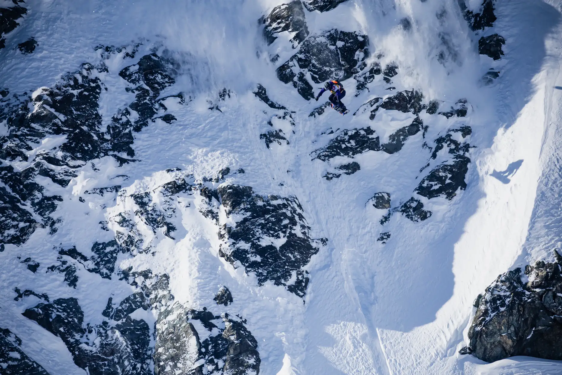 A snowy mountain landscape with rocky cliffs and steep slopes.