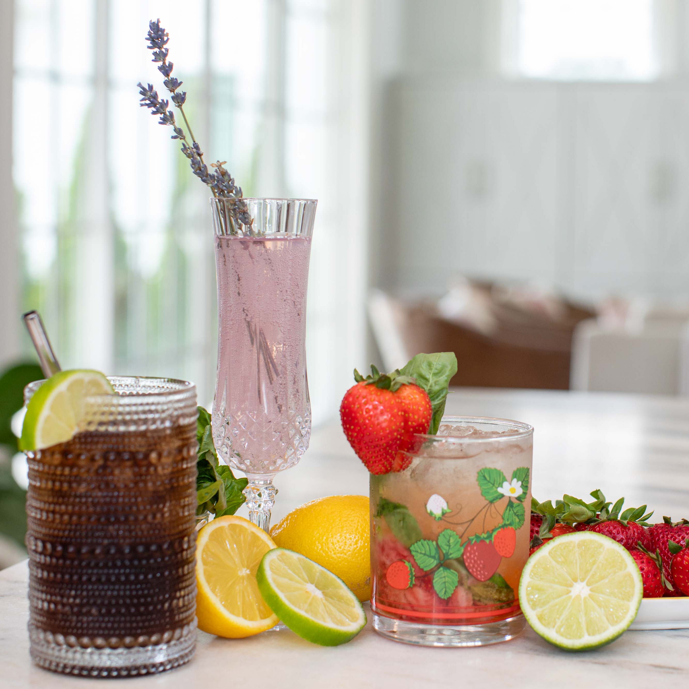 Three mocktails lined up around an array of fruit