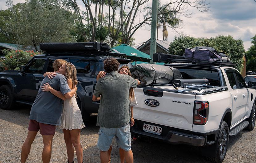People in front of two vehicles setup for camping