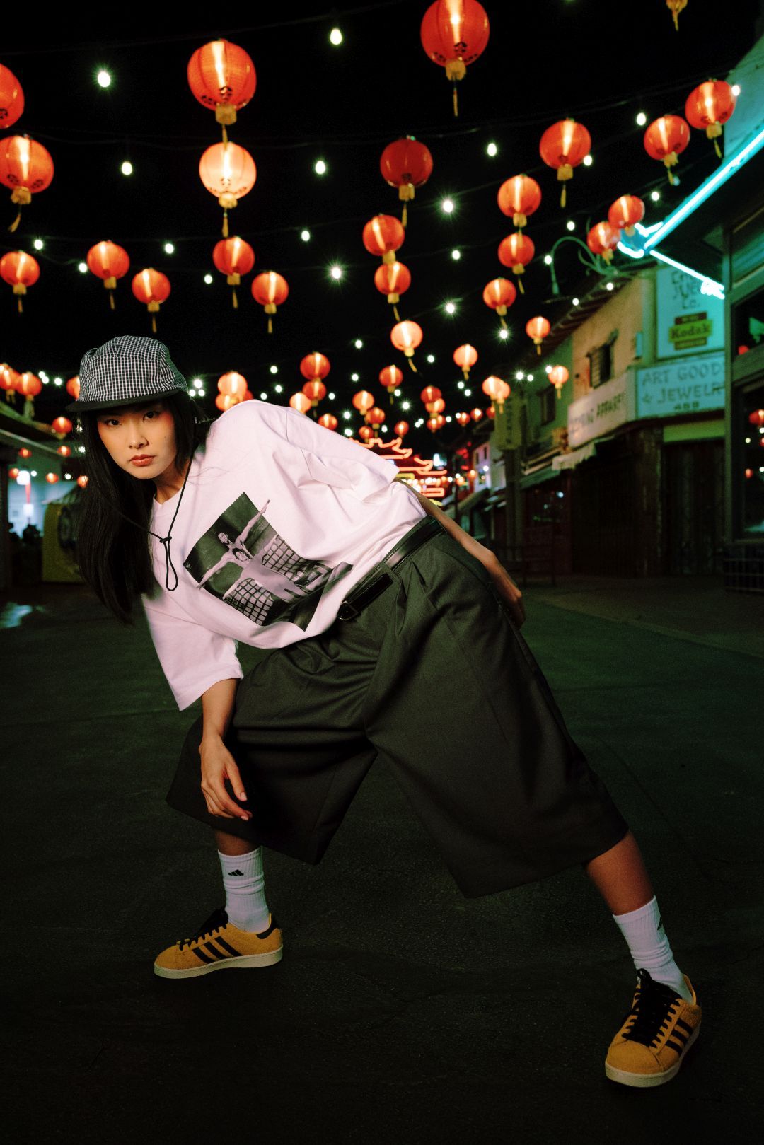 Person posing in street decorated with lanterns at night.