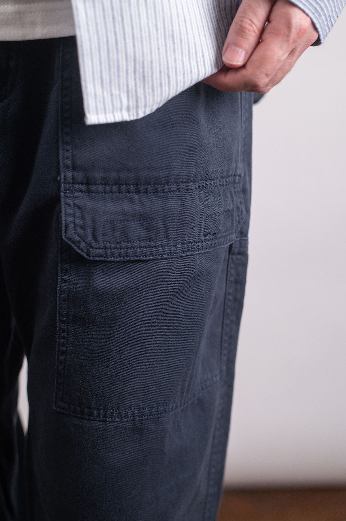 Person wearing a blue shirt, white t-shirt, dark pants, and sneakers.