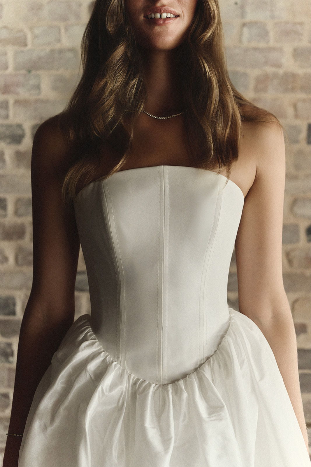 Woman in a strapless white dress with a fitted bodice and flared skirt.