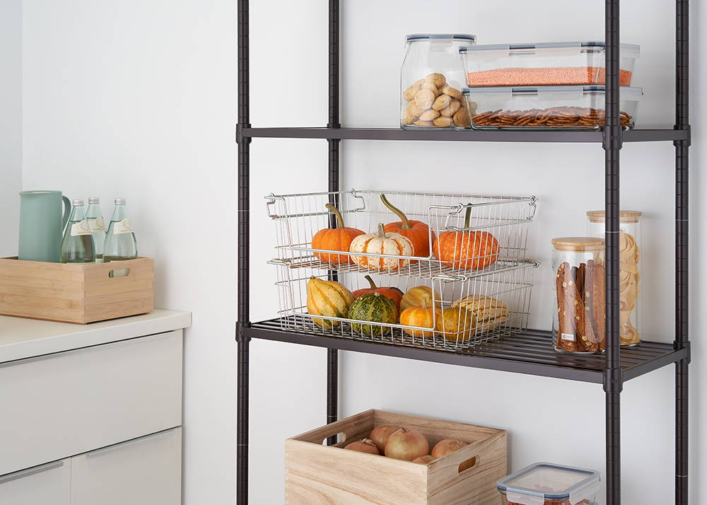Stackable wire baskets on kitchen shelf with items inside