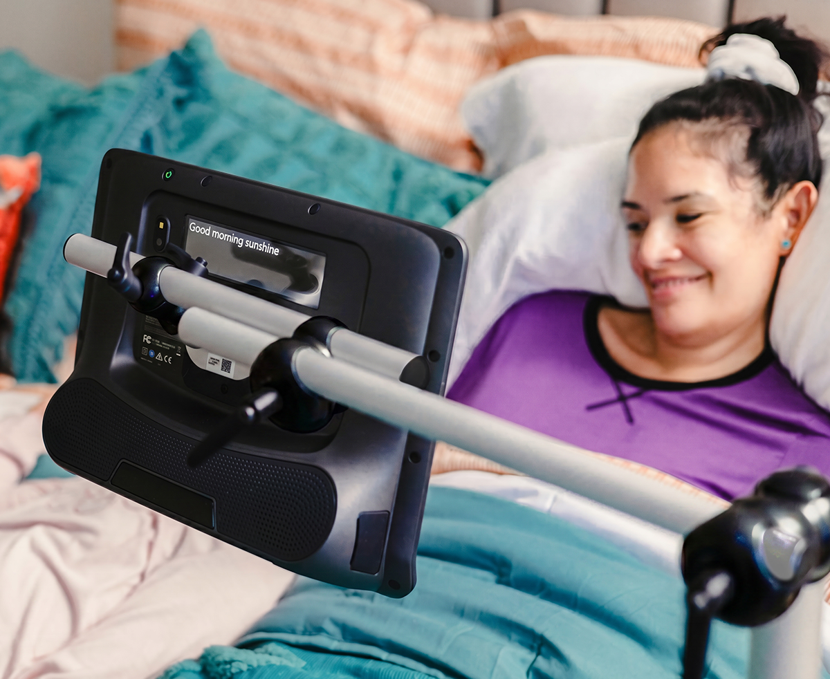 Bodenhalterungen für ein Kommunikationshilfsgerät von Tobii Dynavox, das von einer Frau in ihrem Bett benutzt wird
