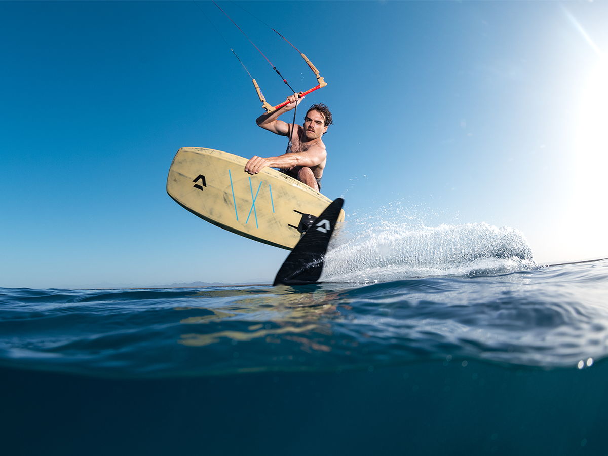 A person surfing on a board with a kite in the ocean.