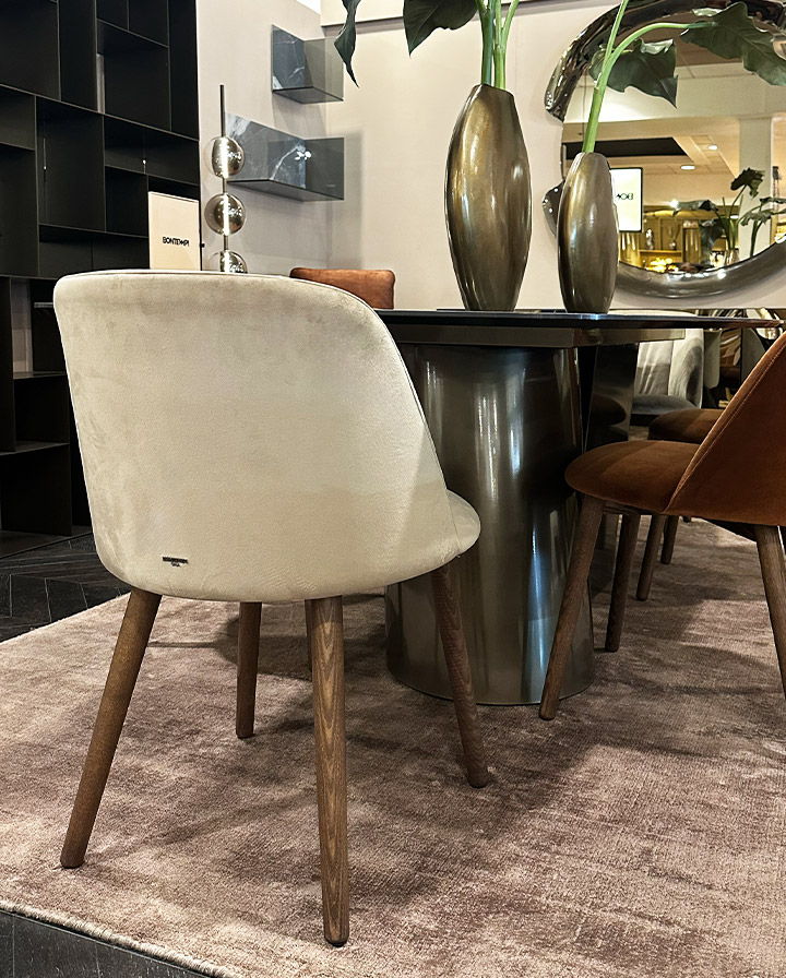 A stylish dining chair beside a round table and decorative vases.