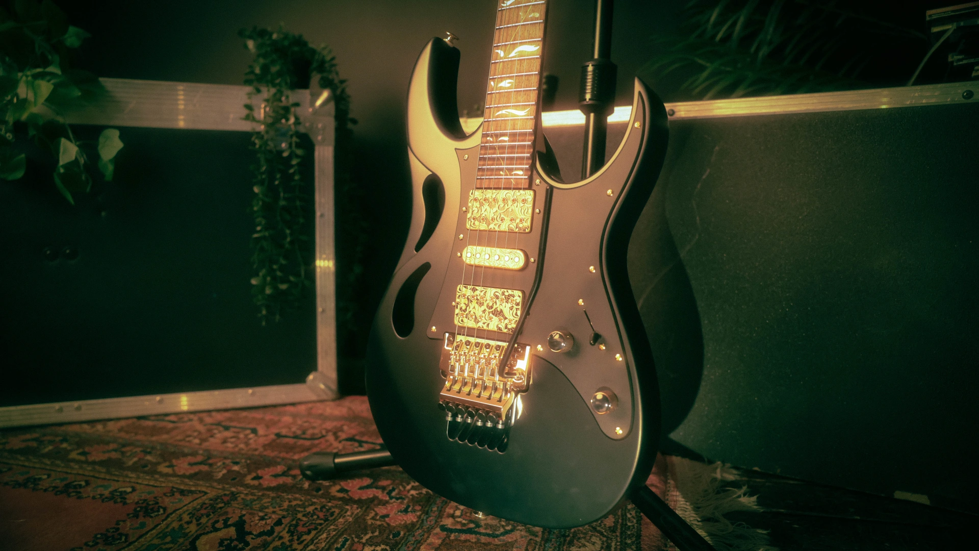 A black Ibanez PIA Steve Vai signature electric guitar leaning against a case with a decorative background.