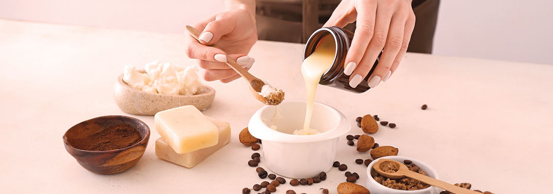 Person pouring a creamy substance into a white bowl with ingredients scattered.