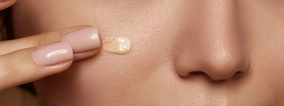 Person applying a foundation with SPF on their cheek.