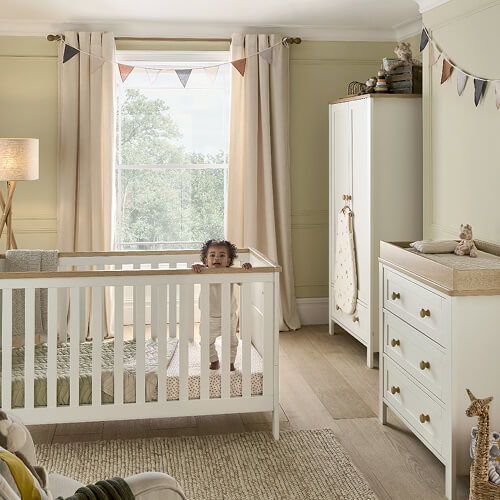 A cozy nursery with a crib, changing table, and window.