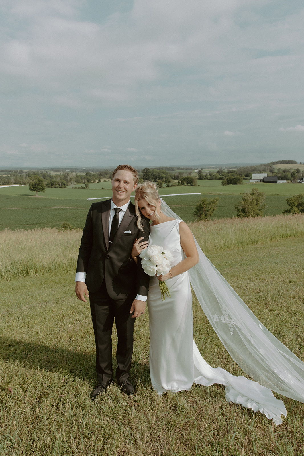Bride and groom posing happily in a scenic outdoor setting.