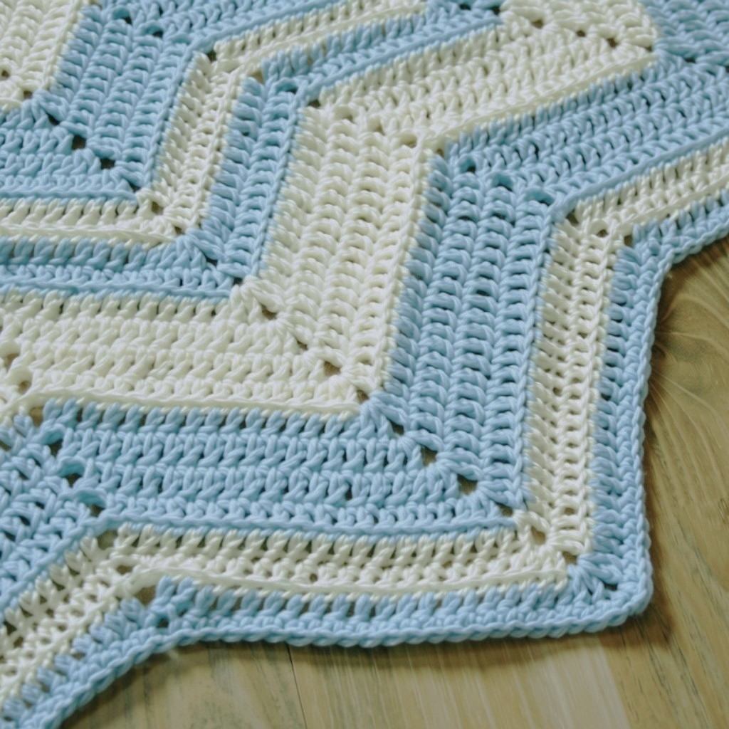 Bildausschnitt von einer blau-weiß-gestreiften Häkeldecke im Zick-Zack-Muster.