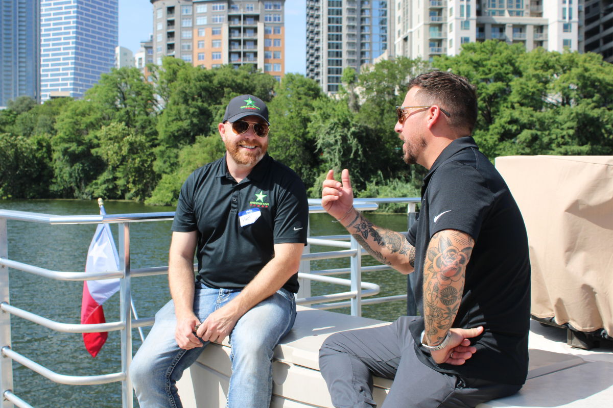 Two people having a conversation on a boat with Austin downtown in the background