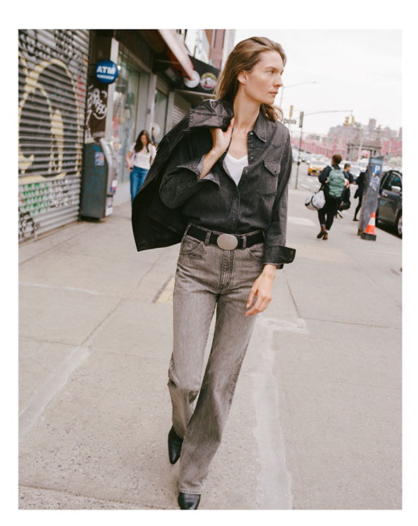 Woman walking on street wearing casual clothing with urban background.
