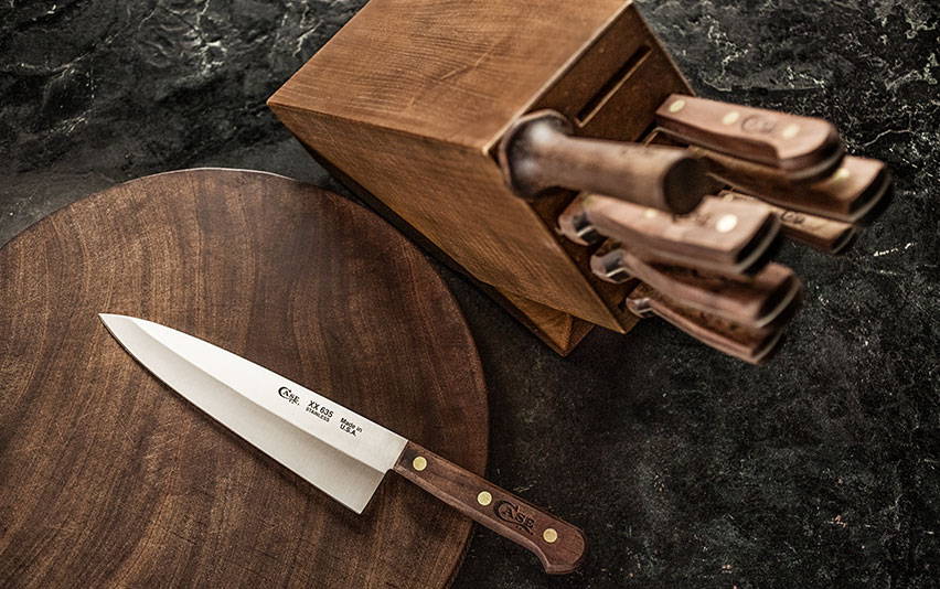 Chef's knife on cutting board with kitchen knife set.